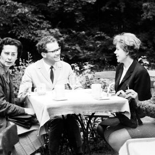 Four people sit at a table outdoors, conversing.
