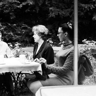 Four people sit at a table outdoors, conversing.