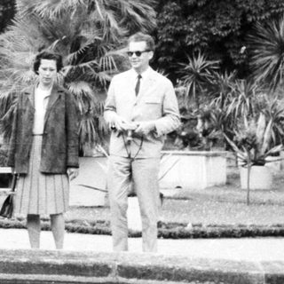 Group of people walk along a garden reflecting pool.