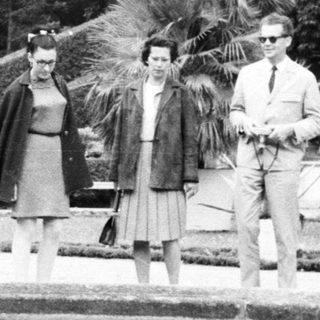 Group of people walk along a garden reflecting pool.