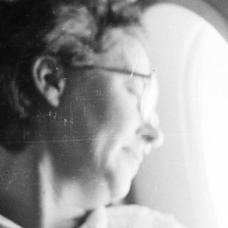 Here's a brief summary of the image: Woman looking out a window in a dimly lit room.