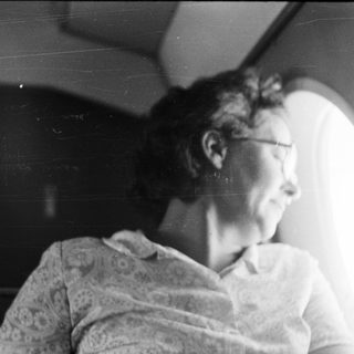 Here's a brief summary of the image: Woman looking out a window in a dimly lit room.