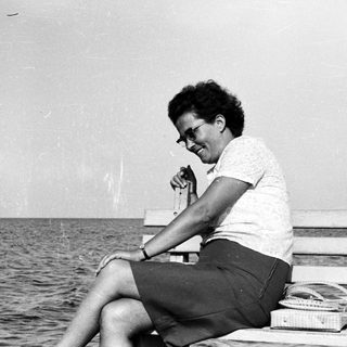 Woman sits on a bench by the ocean.