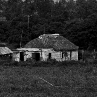 Rural landscape with mountains, buildings, and trees.