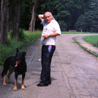 Man walks a Doberman on a road in a park.