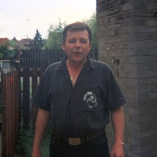 Man stands outside a building with a brick wall.