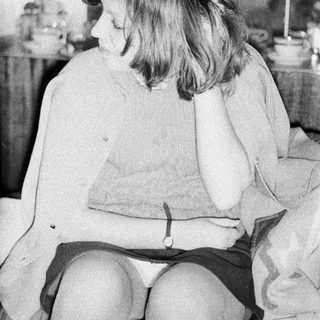 Here's a brief summary of the image: Young girl sits pensively in a kitchen setting.