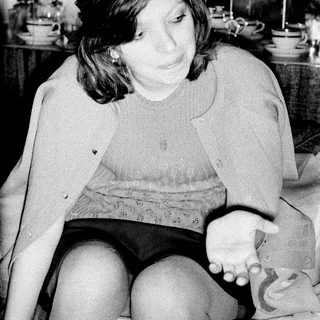 Woman sits with a baby in a kitchen setting.