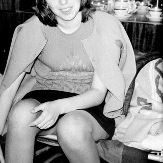 Black and white image of a young woman seated indoors.