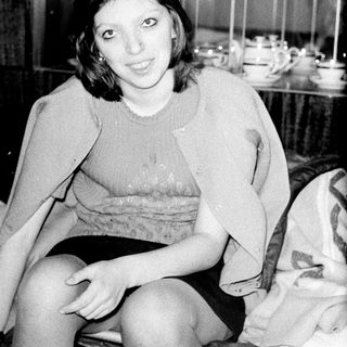 Black and white image of a young woman seated indoors.
