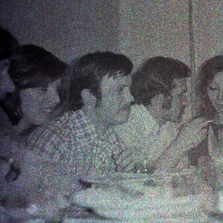 Group seated at a table, dimly lit, appears to be dining.