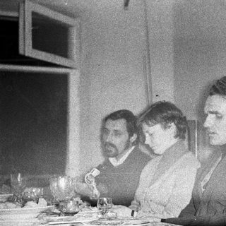 Three people seated at a table, possibly dining.