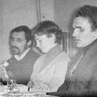Three people seated at a table, possibly dining.