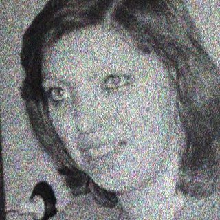 Here's a brief summary of the image: Woman sitting at a table, appearing to look at the camera.