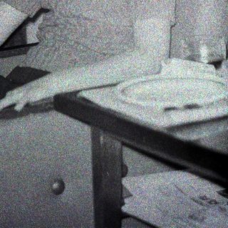 Here's a brief summary of the image: Woman sitting at a table, appearing to look at the camera.