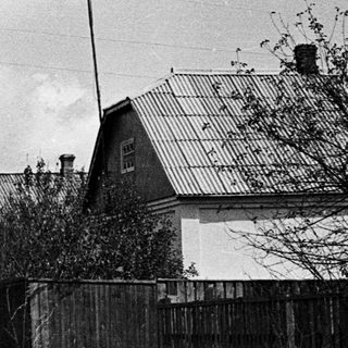 Rural street scene with houses, trees, and a vehicle.