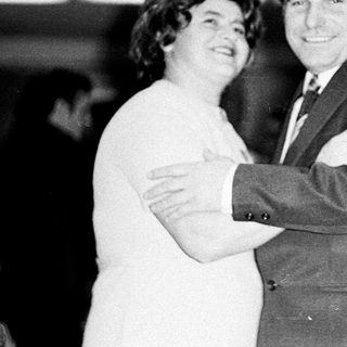 Couple embraces in a formal, black and white portrait.