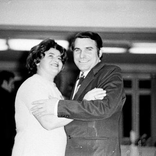 Couple embraces in a formal, black and white portrait.