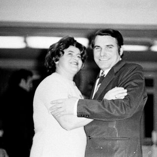 Couple embraces in a formal, black and white portrait.