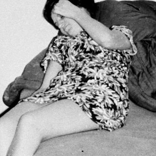 Here's a brief summary of the image: Two women appear distressed in a dimly lit room.