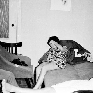 Here's a brief summary of the image: Two women appear distressed in a dimly lit room.