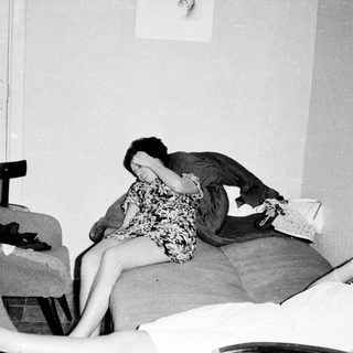 Here's a brief summary of the image: Two women appear distressed in a dimly lit room.