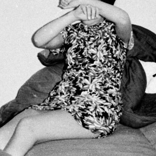 Three young people seated in a sparsely furnished room.