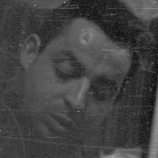 Man looking down, holding something, in a dark setting.
