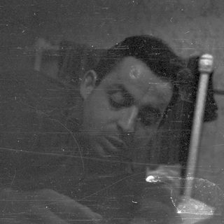 Man looking down, holding something, in a dark setting.