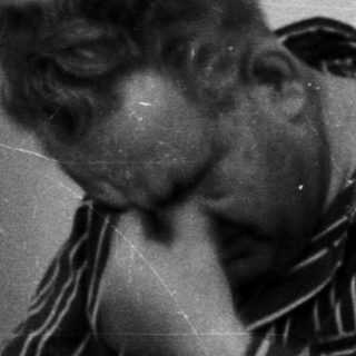 Man in pajamas sits on bed, appearing distressed.