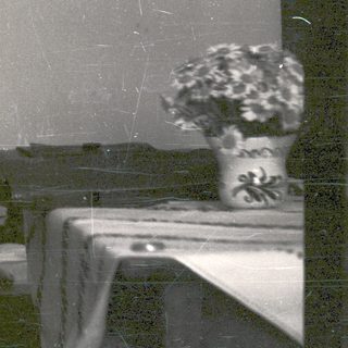 Man in robe seated, appearing to smoke indoors.