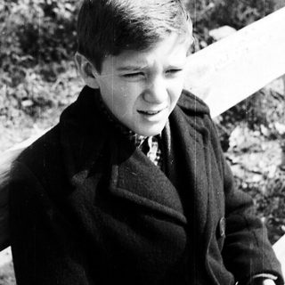 Black and white photo of a young boy in a coat.