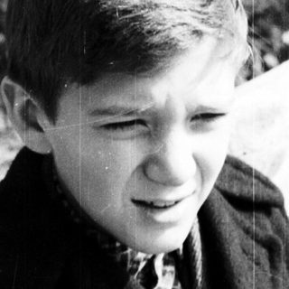 Black and white photo of a young boy in a coat.