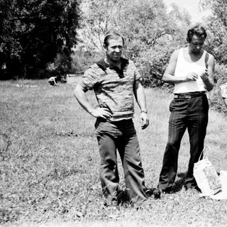 Three people stand in a field, appearing to be outdoors.