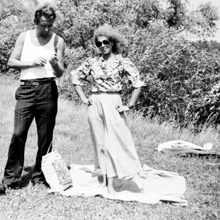 Three people stand in a field, appearing to be outdoors.