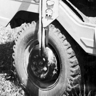 Woman in vintage vehicle, driving outdoors in a grassy area.