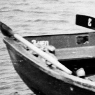 Boy exiting a small boat onto a sandy shoreline.