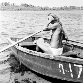 Woman in a boat, rowing on a body of water.