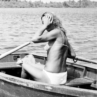 Woman in a boat, rowing on a body of water.