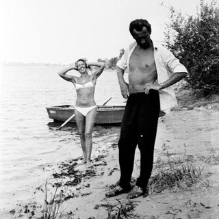 Man and woman near a boat on a shoreline.