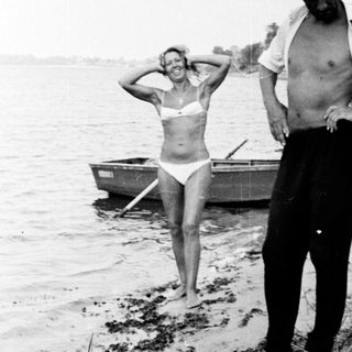 Man and woman near a boat on a shoreline.