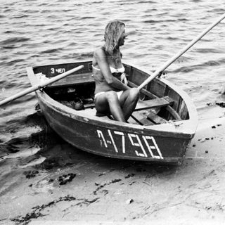 Man and woman near a boat on a sandy shore.
