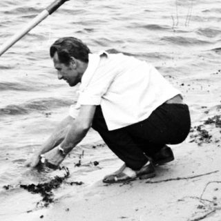 Man and woman near a boat on a sandy shore.