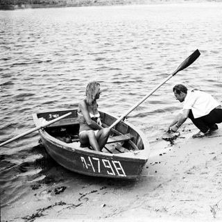 Man and woman near a boat on a sandy shore.