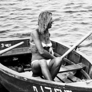 Man and woman near a boat on a sandy shore.
