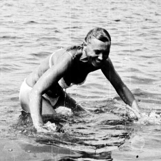 Woman swimming in water with trees in the background.