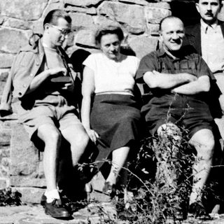 Four men and a woman posing near a stone wall.