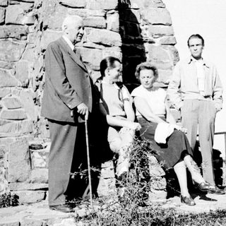 Group of people posing near a stone wall outdoors.