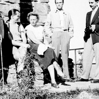 Group of people posing near a stone wall outdoors.