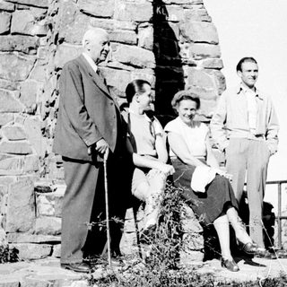 Group of four people standing near a stone wall.